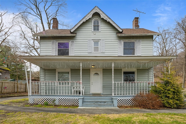 view of front of property with a chimney, a porch, and fence