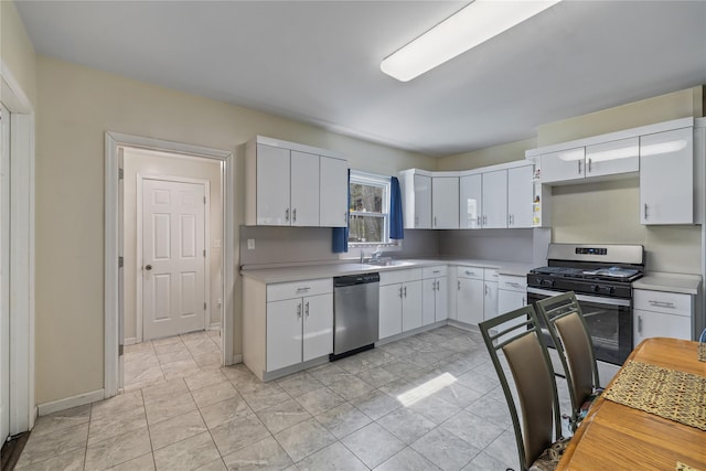 kitchen featuring light countertops, white cabinets, appliances with stainless steel finishes, and a sink
