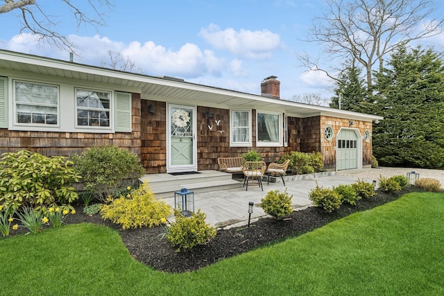view of front facade featuring a front lawn, a chimney, and a garage