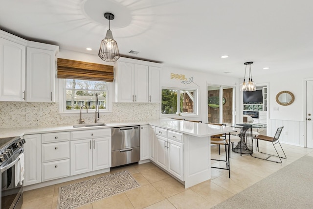 kitchen with appliances with stainless steel finishes, a sink, white cabinetry, and a healthy amount of sunlight