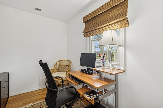 office space featuring wood finished floors, visible vents, and baseboards