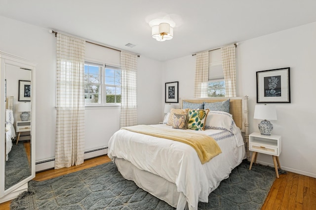 bedroom with visible vents, wood finished floors, and a baseboard radiator
