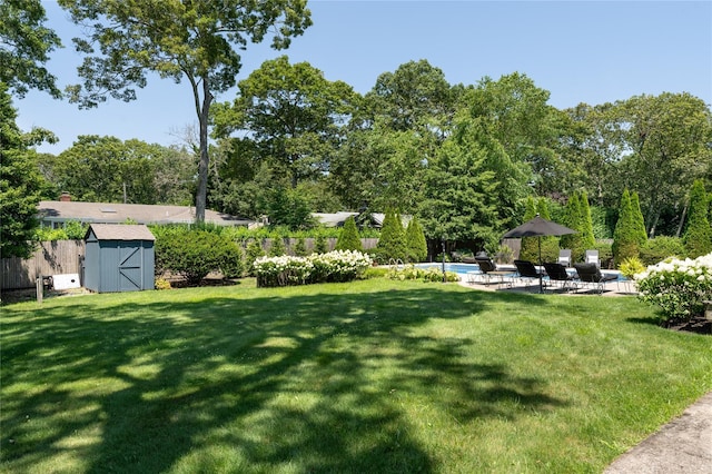 view of yard featuring fence, an outdoor pool, a shed, an outbuilding, and a patio
