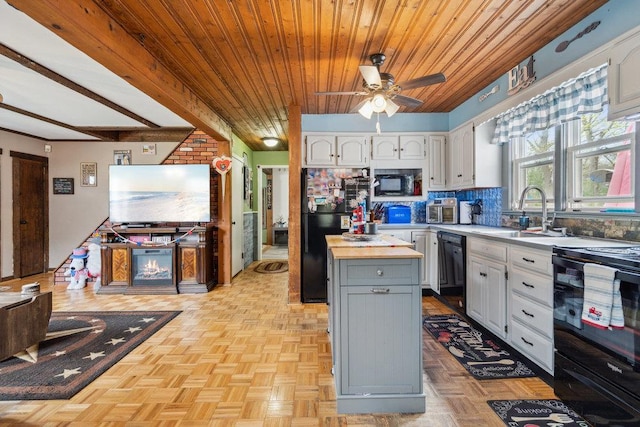 kitchen featuring white cabinets, backsplash, black appliances, and a sink
