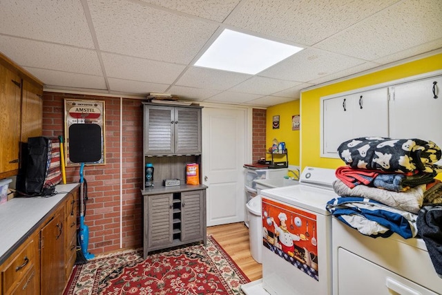 laundry area with light wood-type flooring, washer / clothes dryer, brick wall, and laundry area