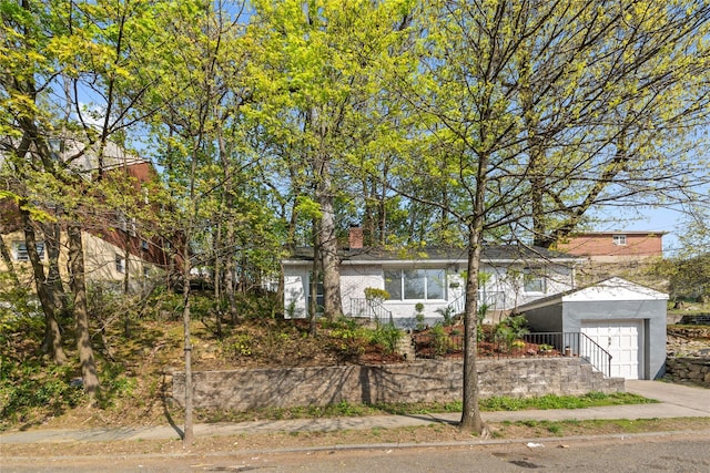 ranch-style house with a chimney, stucco siding, concrete driveway, and an attached garage
