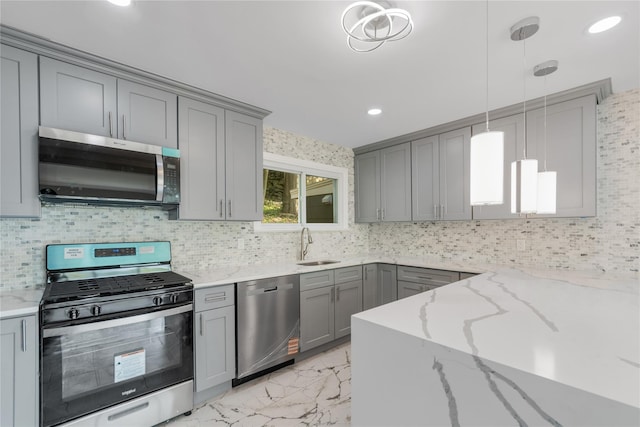 kitchen featuring gray cabinetry, light stone countertops, appliances with stainless steel finishes, and a sink