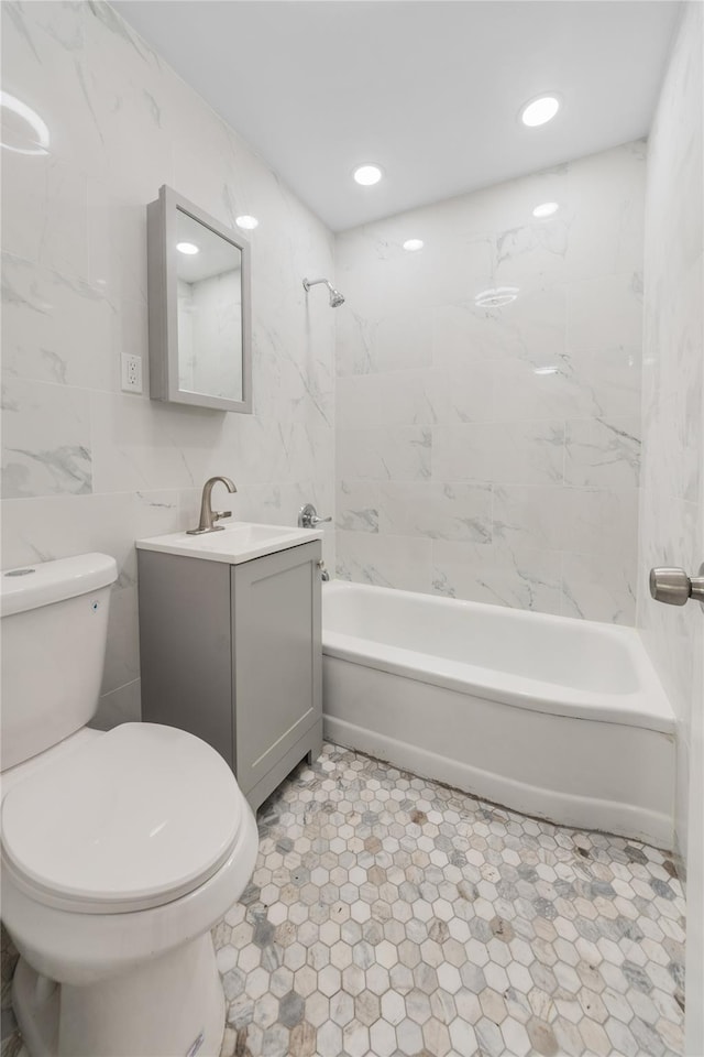 bathroom with toilet, tile walls, shower / bathtub combination, and vanity