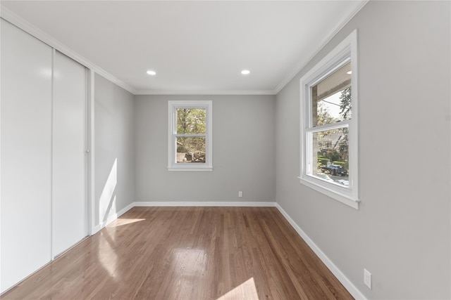 unfurnished room with wood finished floors, recessed lighting, ornamental molding, and baseboards