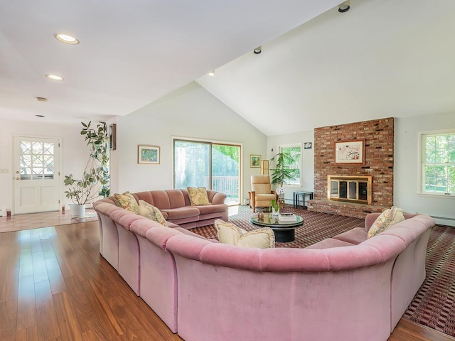 living room featuring lofted ceiling, recessed lighting, a brick fireplace, and wood finished floors