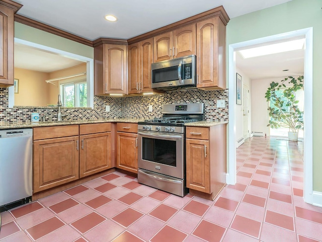 kitchen featuring appliances with stainless steel finishes, tasteful backsplash, light stone countertops, and a sink
