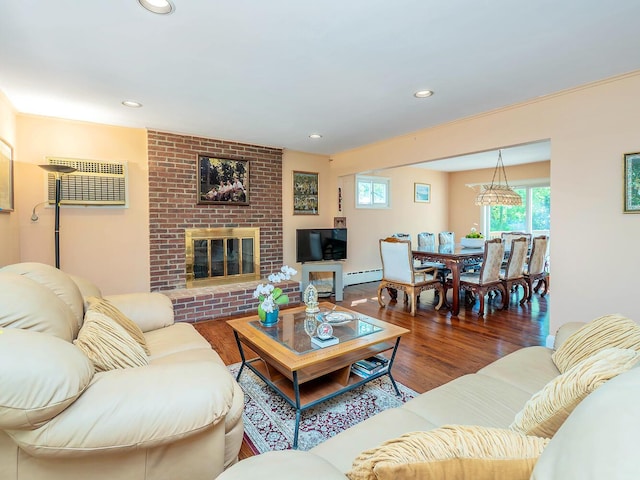 living area with a baseboard radiator, a wall mounted air conditioner, recessed lighting, a brick fireplace, and wood finished floors