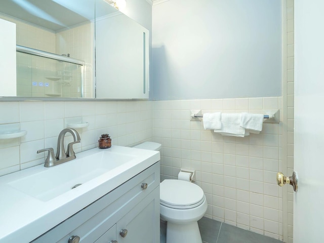 bathroom with toilet, vanity, tile walls, and a shower stall