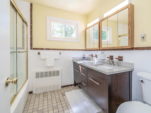 full bathroom with radiator, tile walls, toilet, and a sink