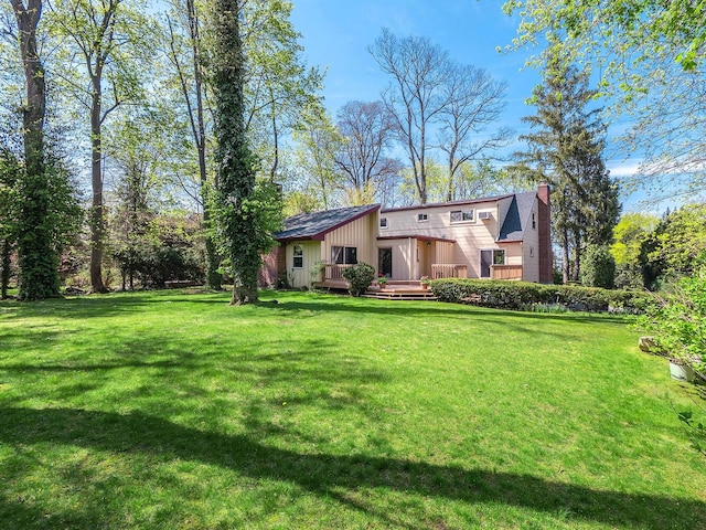 view of front of property featuring a front yard, a chimney, and a deck