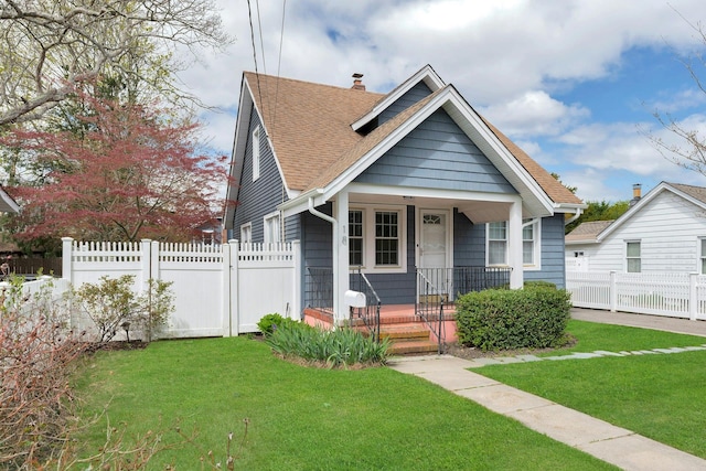 bungalow-style house featuring fence, roof with shingles, covered porch, and a front yard