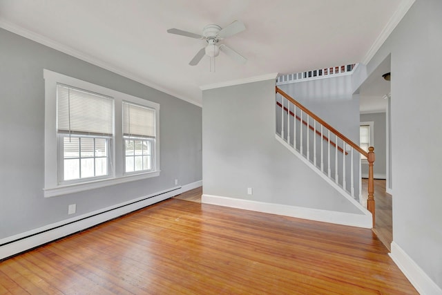 spare room with baseboard heating, light wood-type flooring, and crown molding