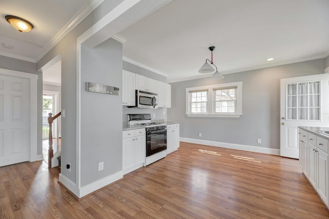 kitchen featuring white cabinetry, gas range oven, plenty of natural light, and stainless steel microwave