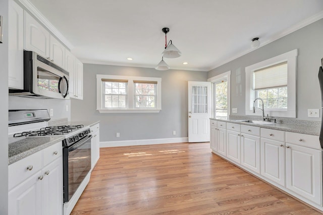 kitchen featuring stainless steel microwave, white cabinets, ornamental molding, a sink, and range with gas cooktop