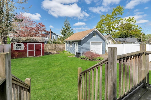 view of yard featuring a fenced backyard, a detached garage, central air condition unit, and an outbuilding