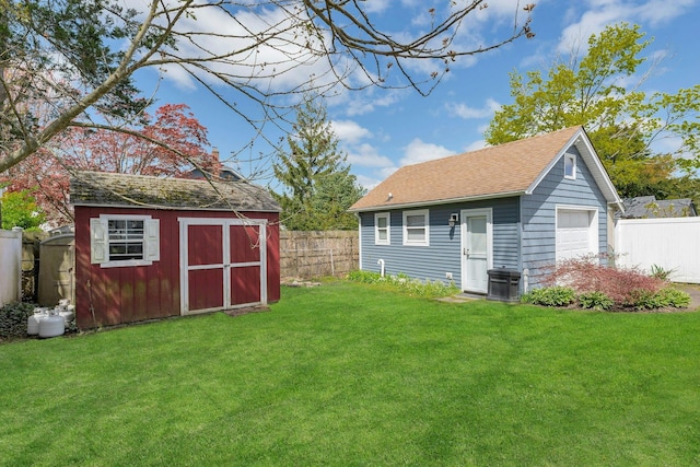 view of outdoor structure with an outdoor structure, central AC, and a fenced backyard