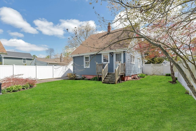rear view of property featuring a gate, a yard, a chimney, and a fenced backyard