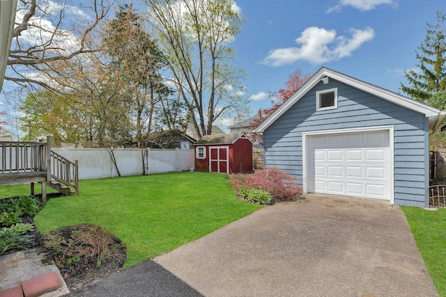 view of yard featuring concrete driveway, an outbuilding, a storage shed, fence, and a garage