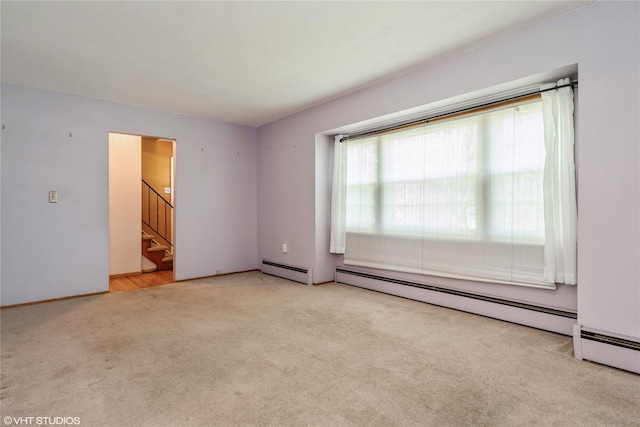 empty room featuring carpet floors, baseboards, stairs, and a baseboard radiator