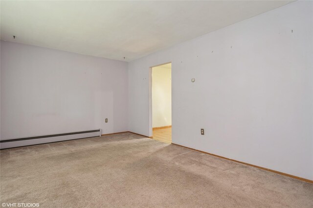spare room with light colored carpet, baseboards, and baseboard heating