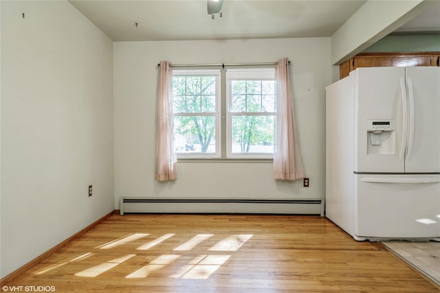 unfurnished dining area featuring light wood-style flooring and a baseboard heating unit