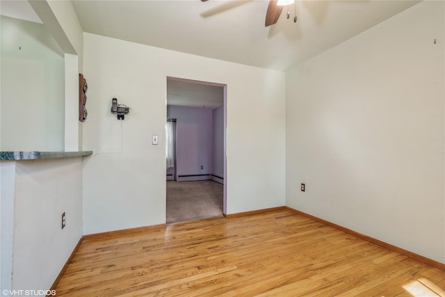 spare room featuring baseboards, ceiling fan, and light wood finished floors