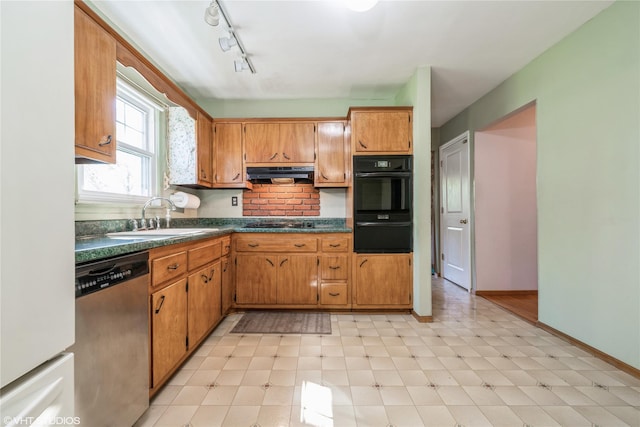 kitchen with dark countertops, stainless steel dishwasher, a sink, freestanding refrigerator, and under cabinet range hood