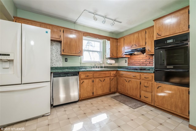 kitchen featuring dark countertops, a sink, black appliances, under cabinet range hood, and a warming drawer