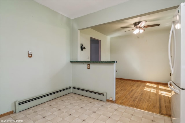 spare room featuring baseboards, a baseboard radiator, and a ceiling fan