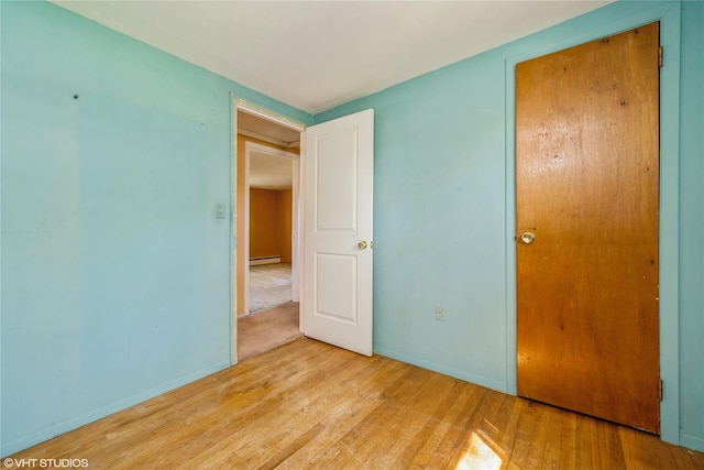 unfurnished bedroom featuring baseboards, baseboard heating, and wood finished floors