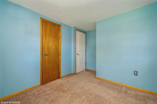 spare room with baseboards and light colored carpet