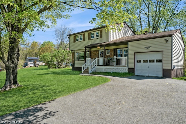 traditional home featuring a porch, an attached garage, driveway, and a front yard