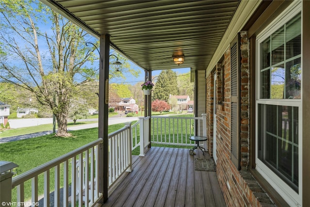 wooden terrace featuring a porch and a lawn