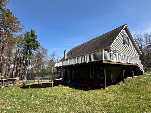 487 Southwoods Dr, Monticello, NY 12701 - rear view of property with a chimney, a wooden deck, a yard, and a trampoline
