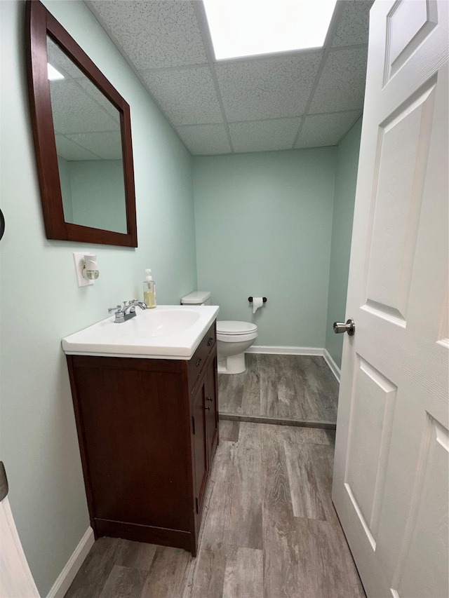 487 Southwoods Dr, Monticello, NY 12701 - bathroom featuring toilet, a drop ceiling, baseboards, wood finished floors, and vanity
