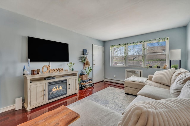 living room with a baseboard heating unit, baseboards, a glass covered fireplace, dark wood-type flooring, and a wall mounted air conditioner