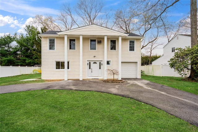 greek revival house with fence, an attached garage, a front yard, and aphalt driveway