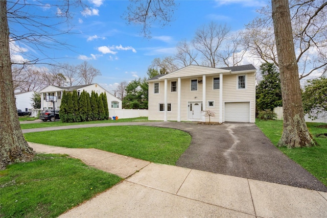 greek revival inspired property with fence, an attached garage, driveway, and a front lawn