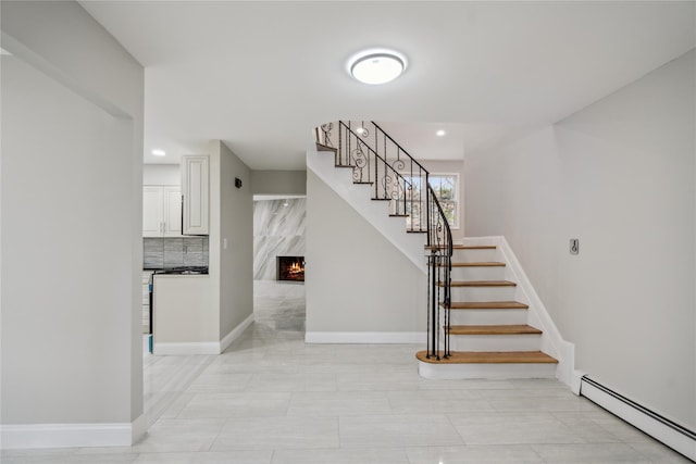 staircase featuring baseboards, recessed lighting, a baseboard heating unit, and a premium fireplace