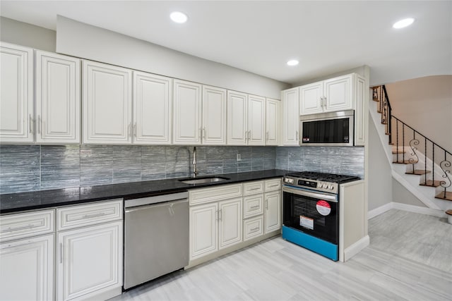 kitchen with tasteful backsplash, a sink, stainless steel appliances, recessed lighting, and white cabinetry