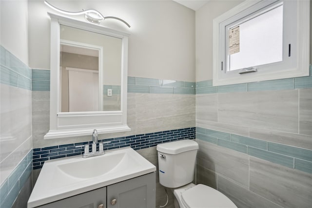 half bathroom with tile walls, vanity, and toilet