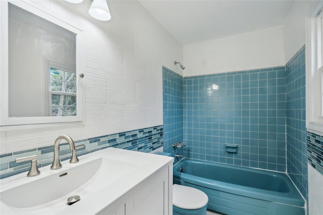 bathroom with vanity, toilet, tile walls, washtub / shower combination, and backsplash
