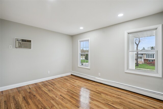 empty room with baseboard heating, an AC wall unit, recessed lighting, baseboards, and wood finished floors