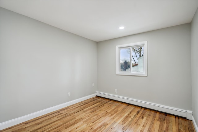 empty room with baseboards, a baseboard radiator, wood finished floors, and recessed lighting