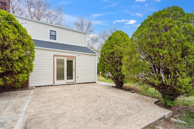 back of property with a shingled roof and a patio area